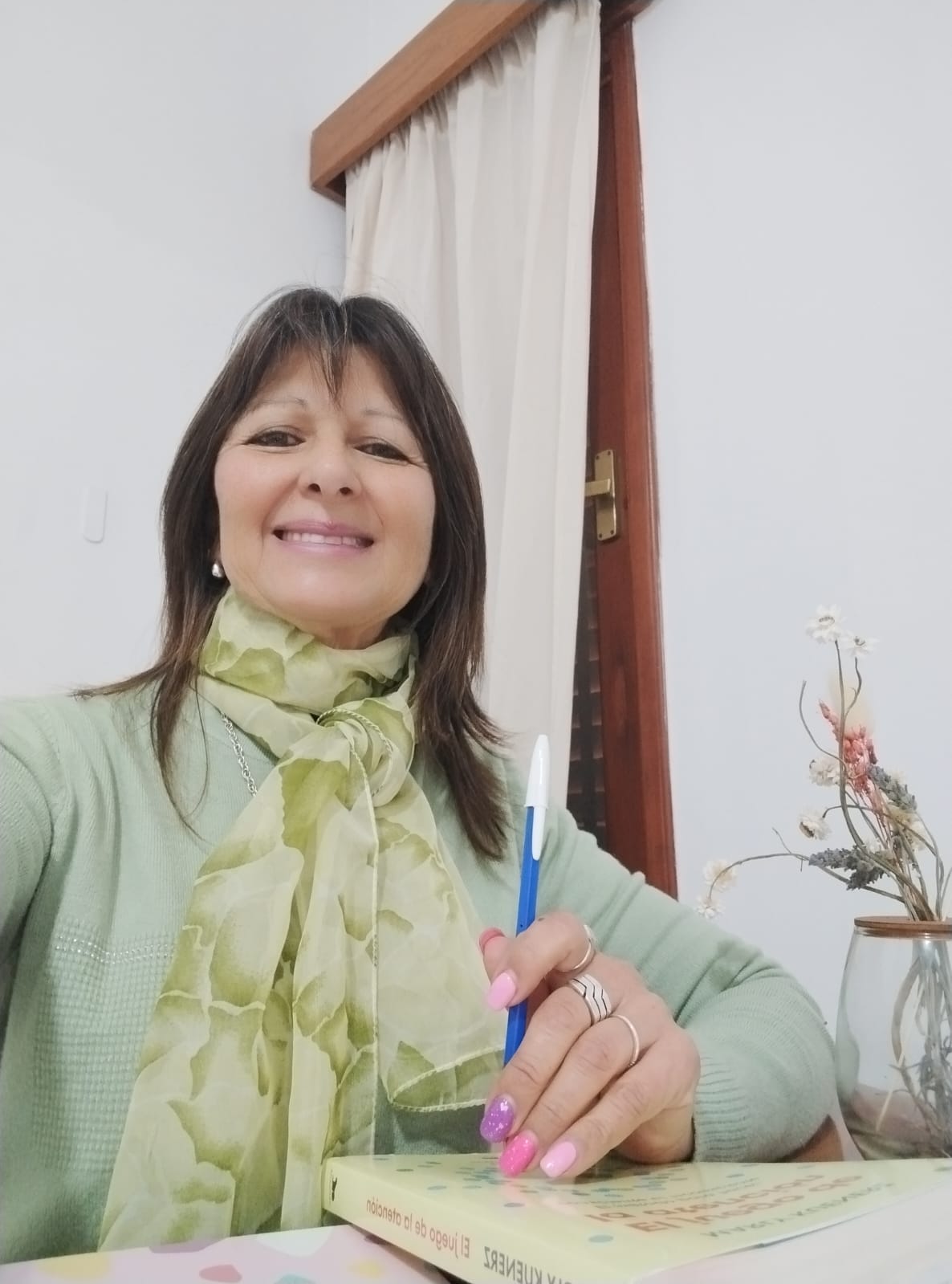Olga Ledezma escribiendo junto a uno de sus libros